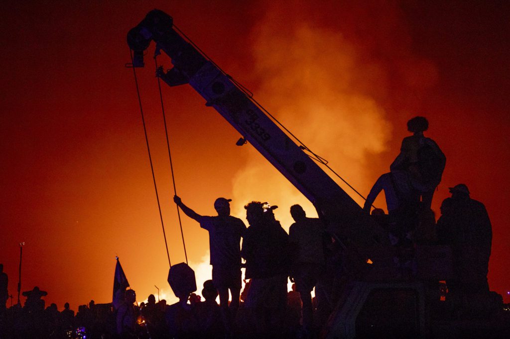 People lounging on crane in front of Temple Burn at Burning Man