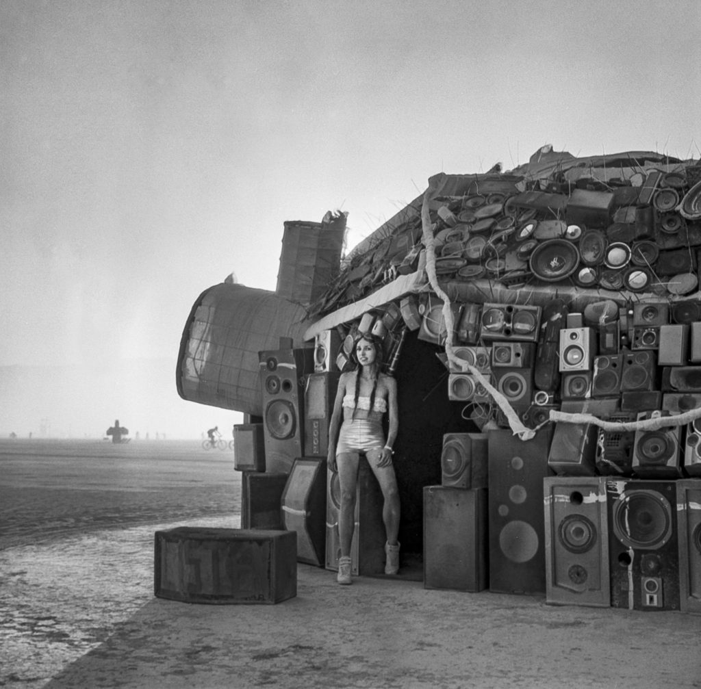 Building made of speakers with artist posing at Burning Man
